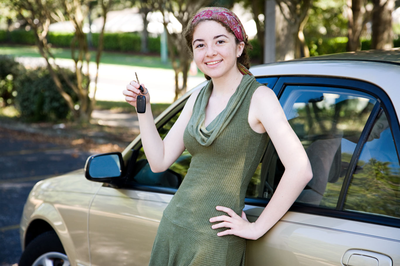 young woman leaning on a car holding car keys