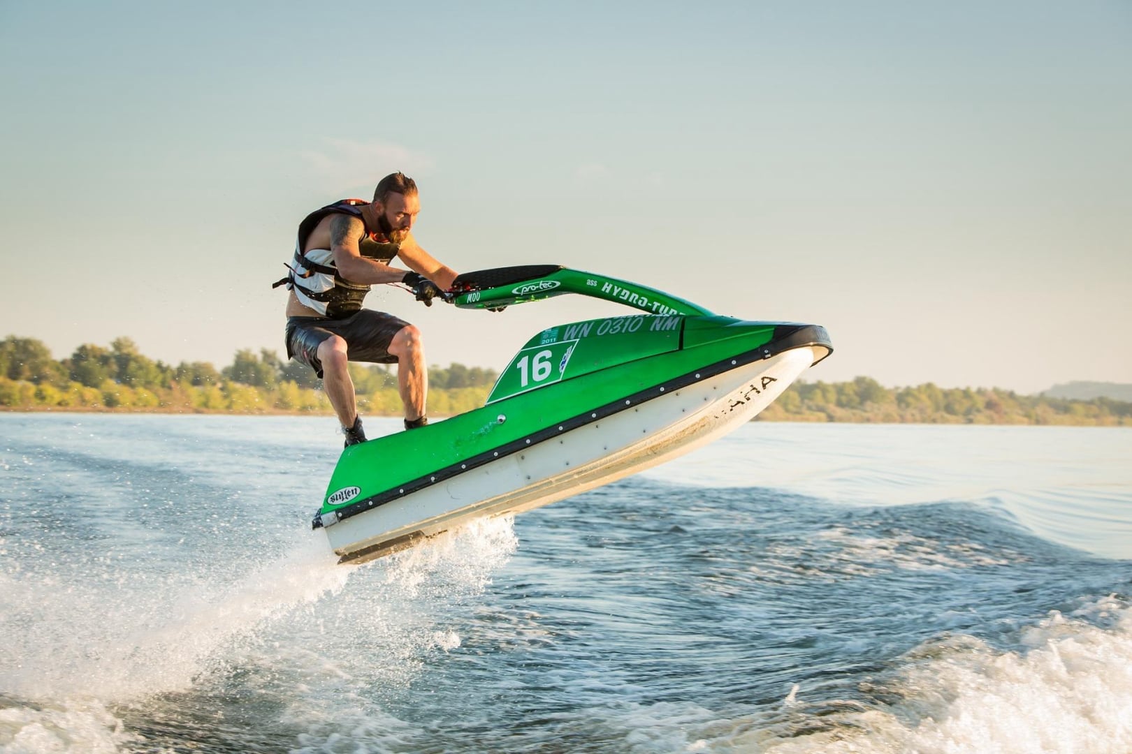 A man on a green jet sky jumping a wave in ocean