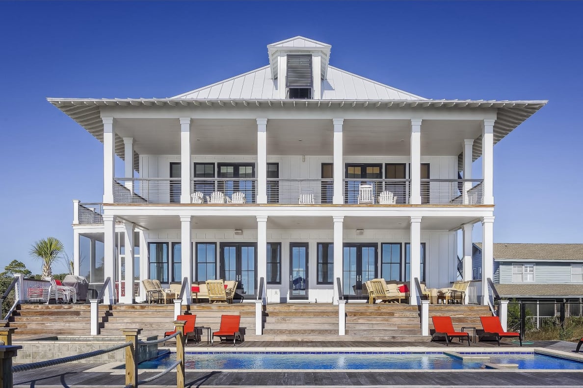 back yard of a 2 story white house with a pool