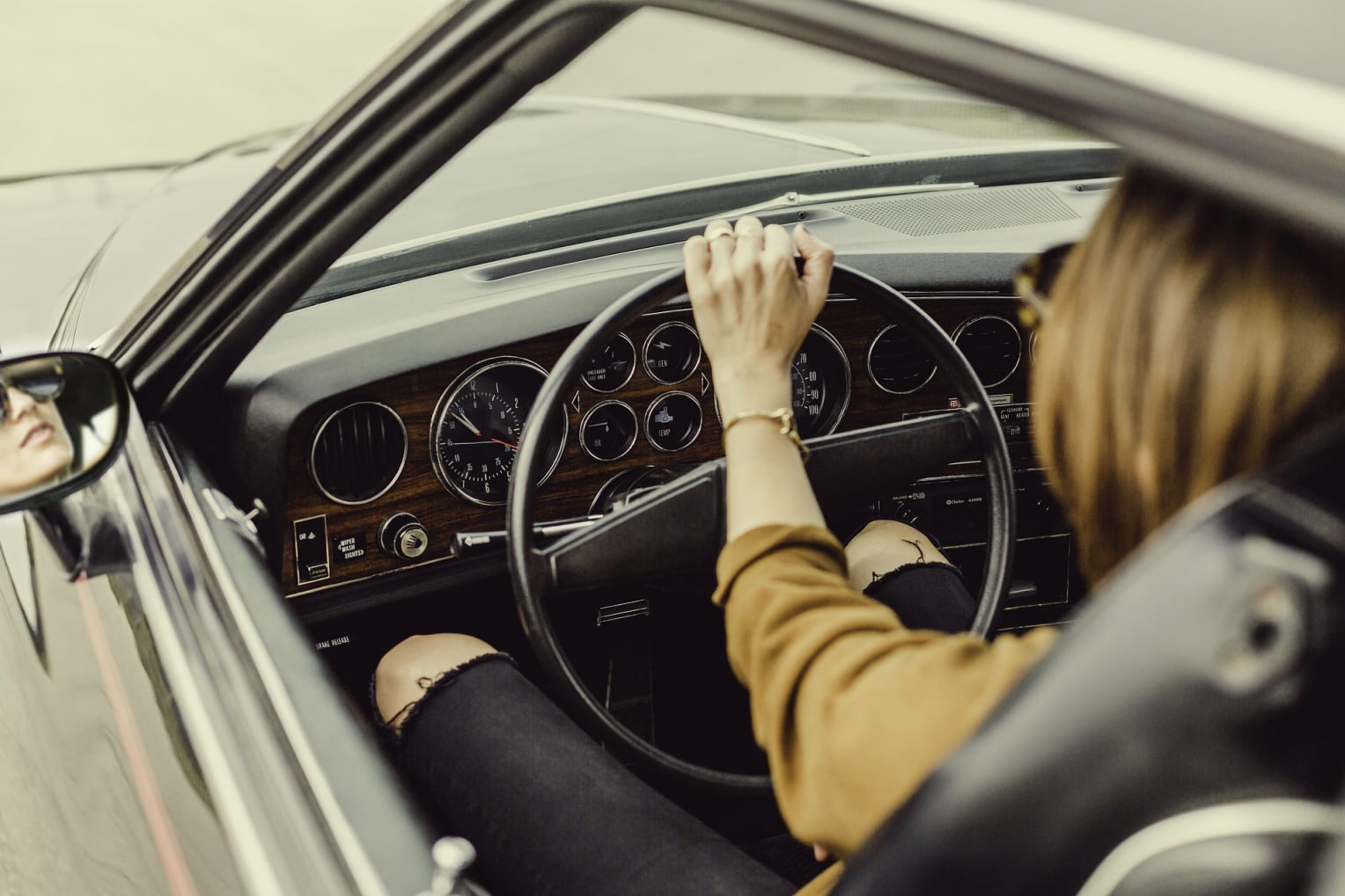 woman driving in a car on the road wear tan shirt , grey colored car