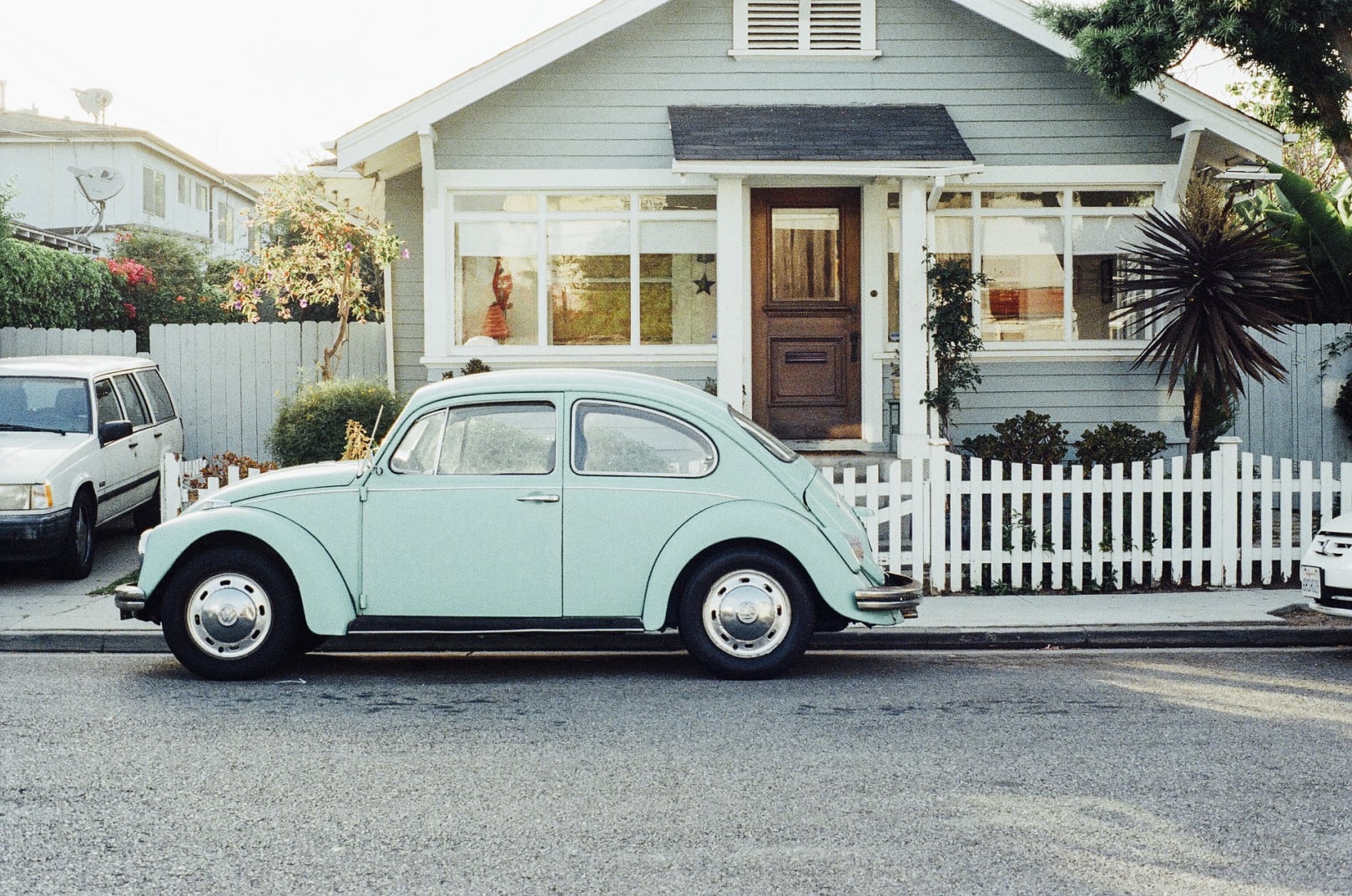 light blue vw bug car in front of a mint green house
