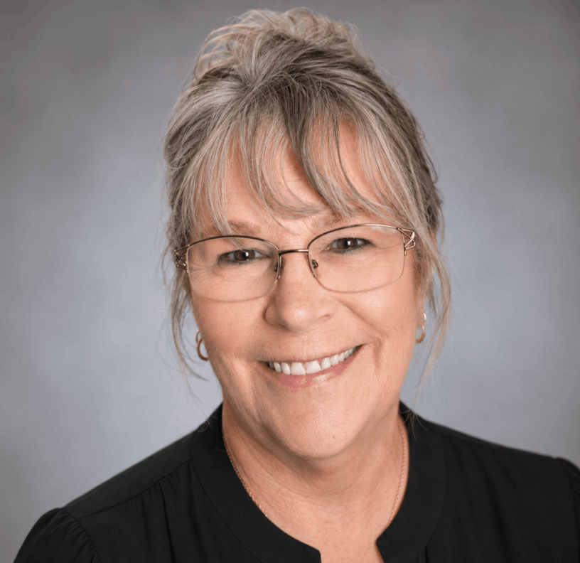 Judy McMahan wearing glasses in a black shirt with gray background